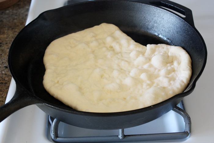 cooking butter garlic naan in cast iron skillet