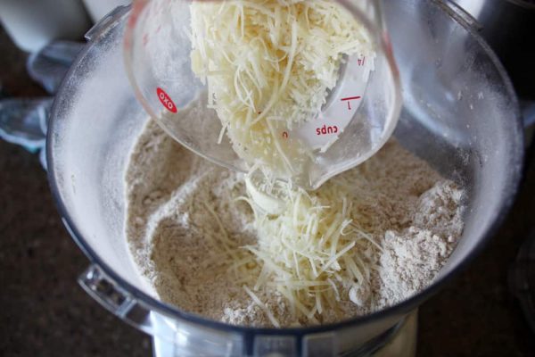 adding parmesan cheese to the cracker dough in blender.