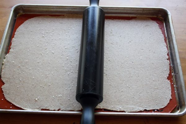 rolling cracker dough on baking sheet.
