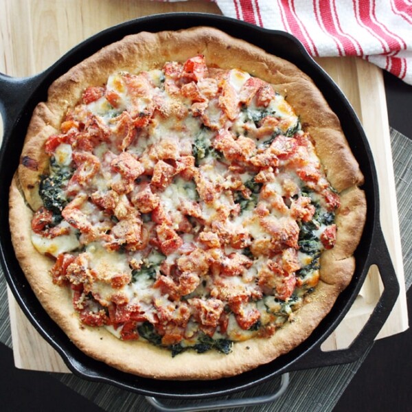 deep dish spinach tomato pizza in cast iron skillet.
