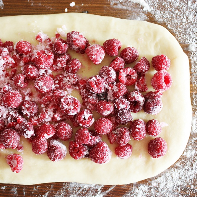 raspberry filling on rolled out sweet dough for raspberry cinnamon rolls.