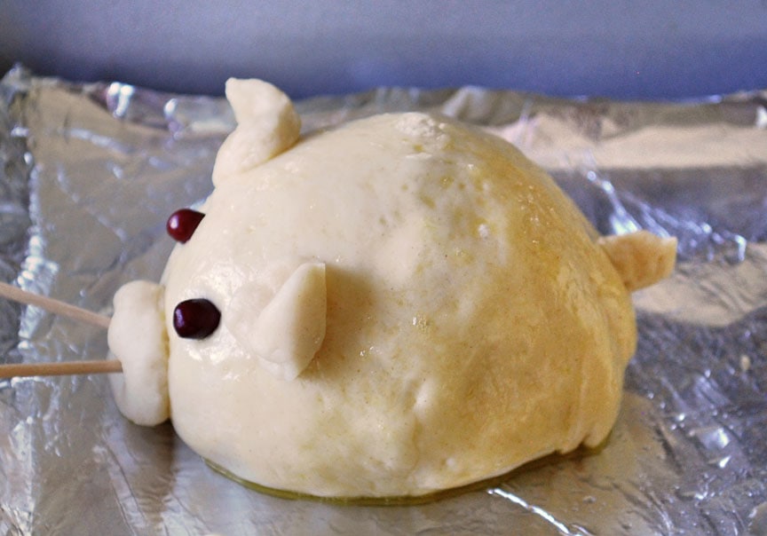 side view of sausage stuffed piglet bun on baking sheet