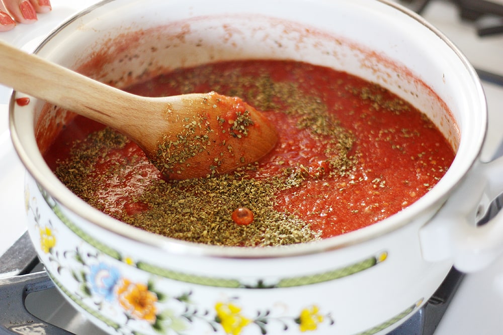 stirring herbs into sauce pot