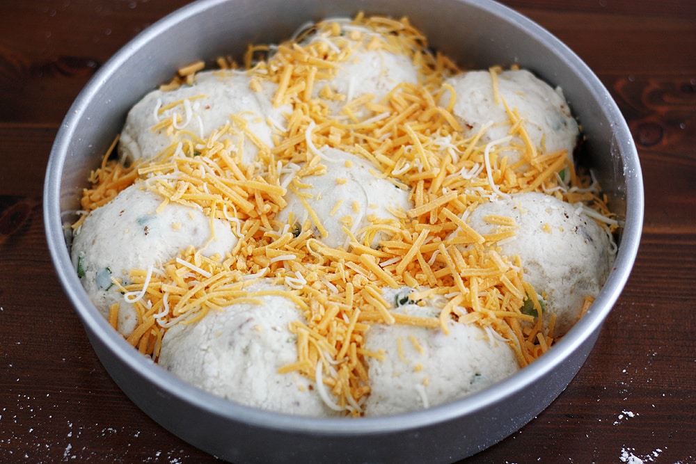 topping loaded mashed potato biscuit dough with cheese in pan