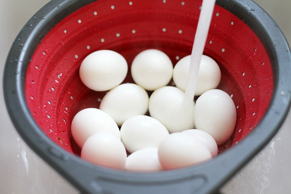running hard boiled eggs under cold water in colander