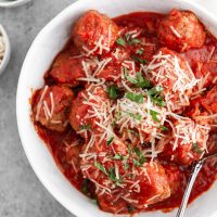 slow cooker italian meatballs in a bowl with cheese and basil on top