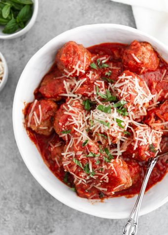 slow cooker italian meatballs in a bowl with cheese and basil on top