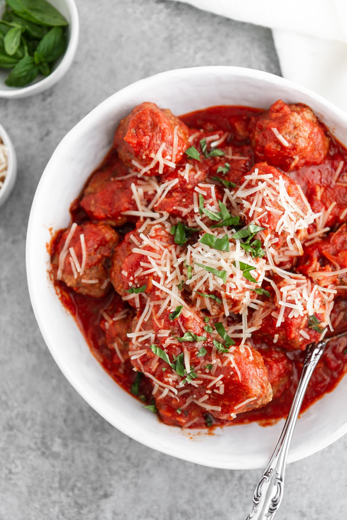 slow cooker italian meatballs in a bowl with cheese and basil on top