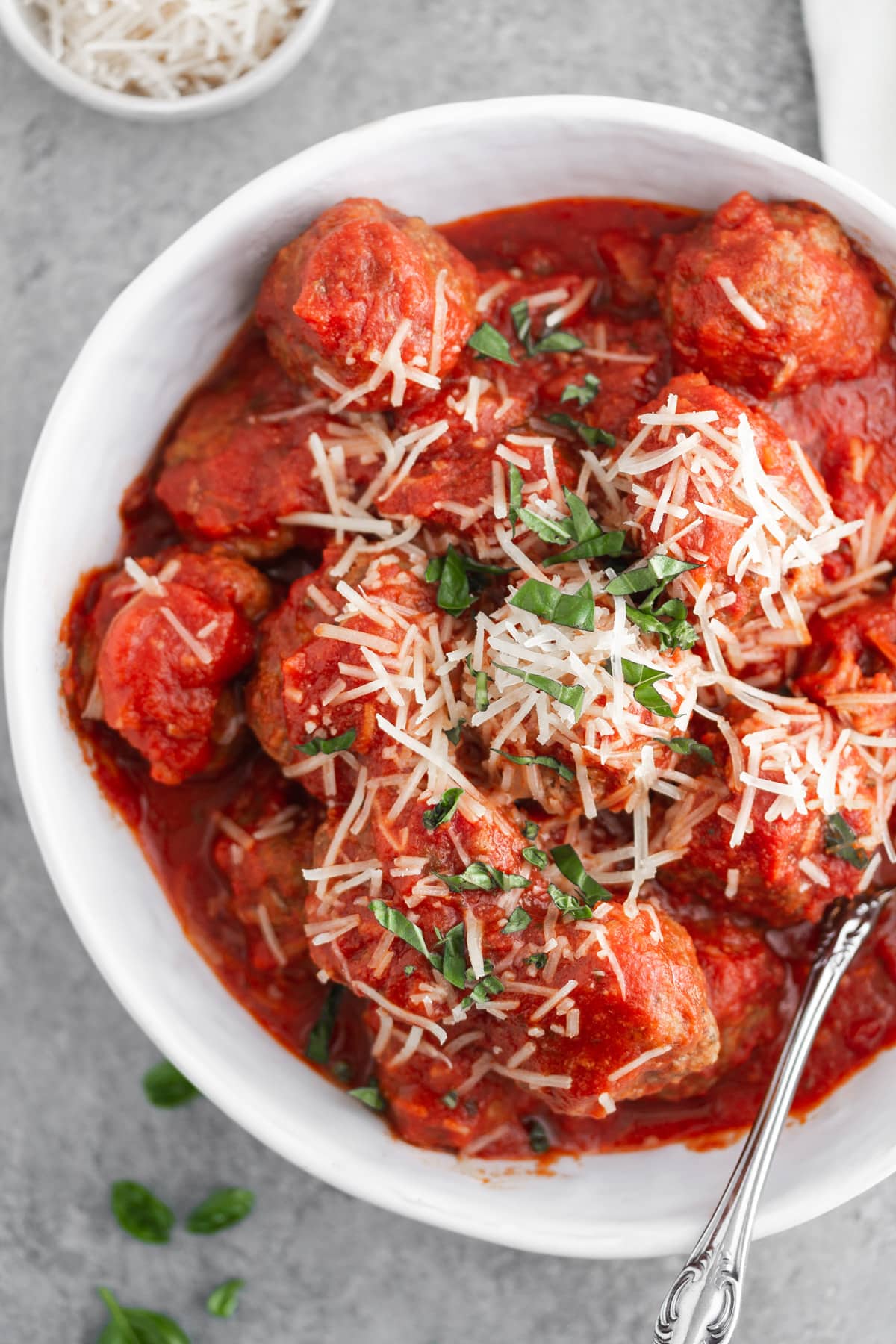 slow cooker italian meatballs in a bowl with cheese and basil on top