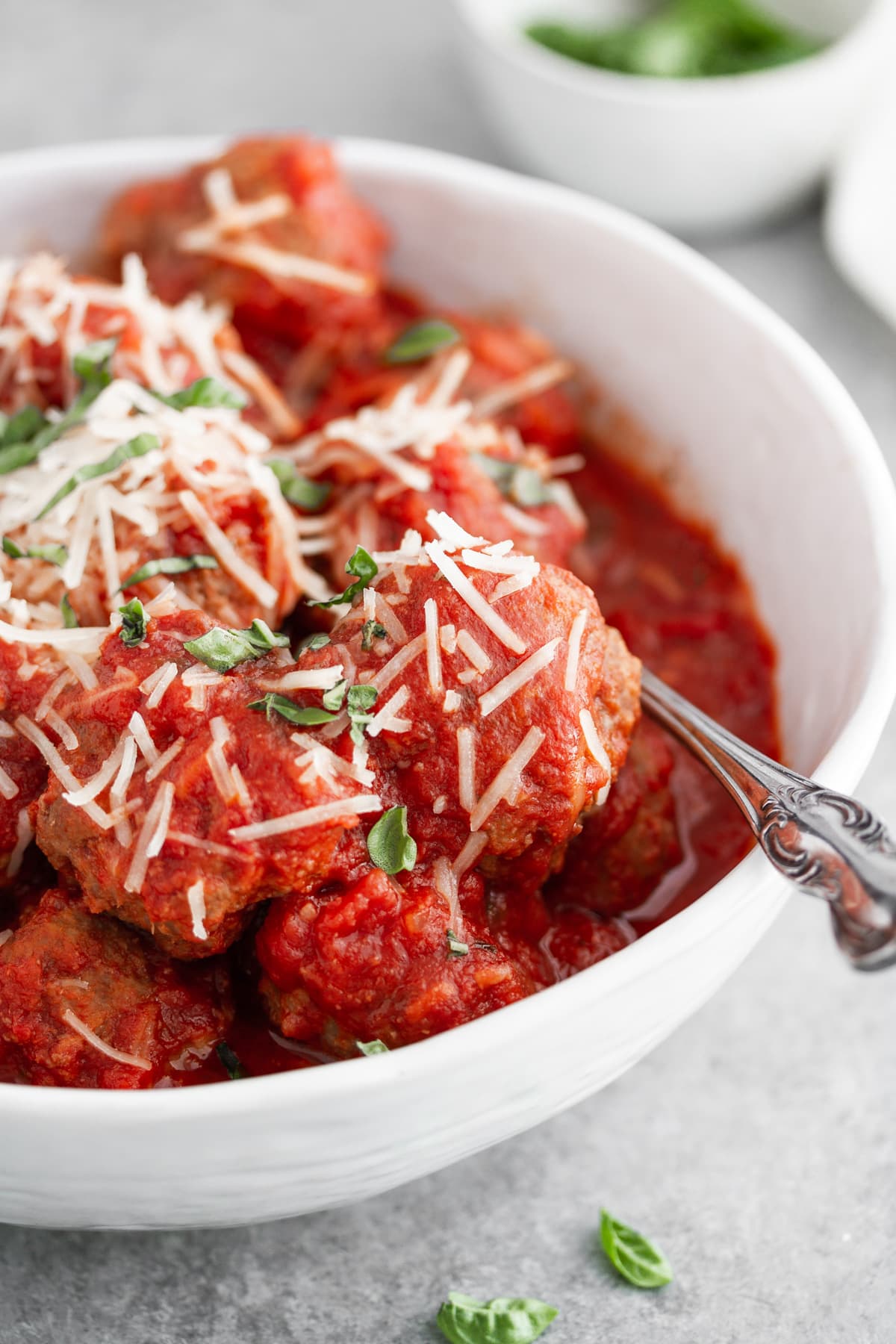 slow cooker italian meatballs in a bowl with cheese and basil on top