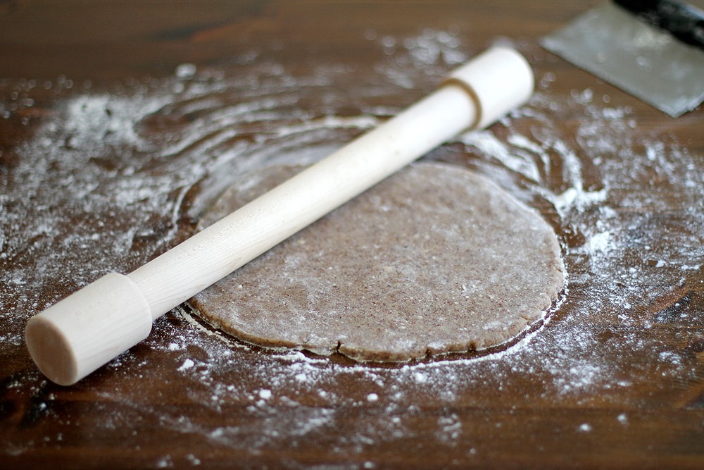 rolling out pie dough for ginger plum pie