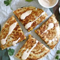 quesadilla on parchment paper with crema drizzled