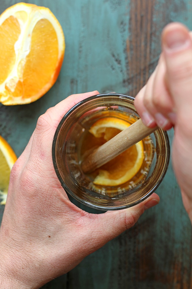 muddling orange in a cocktail glass