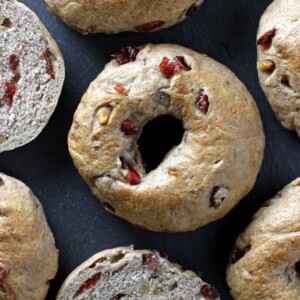 cranberry bagels on dark surface some sliced.