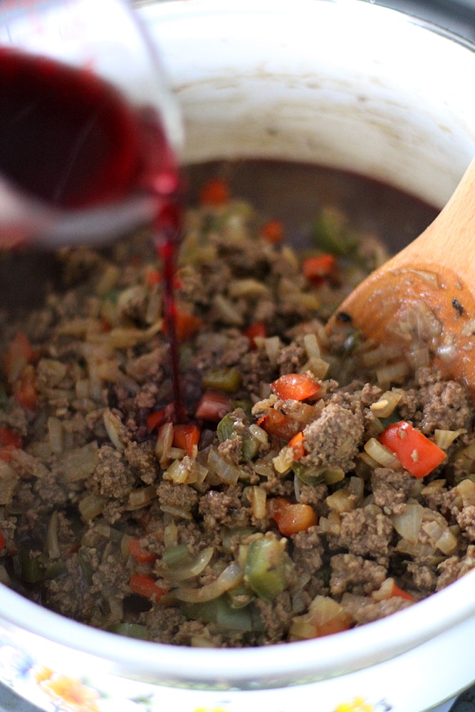 pouring red wine into chili