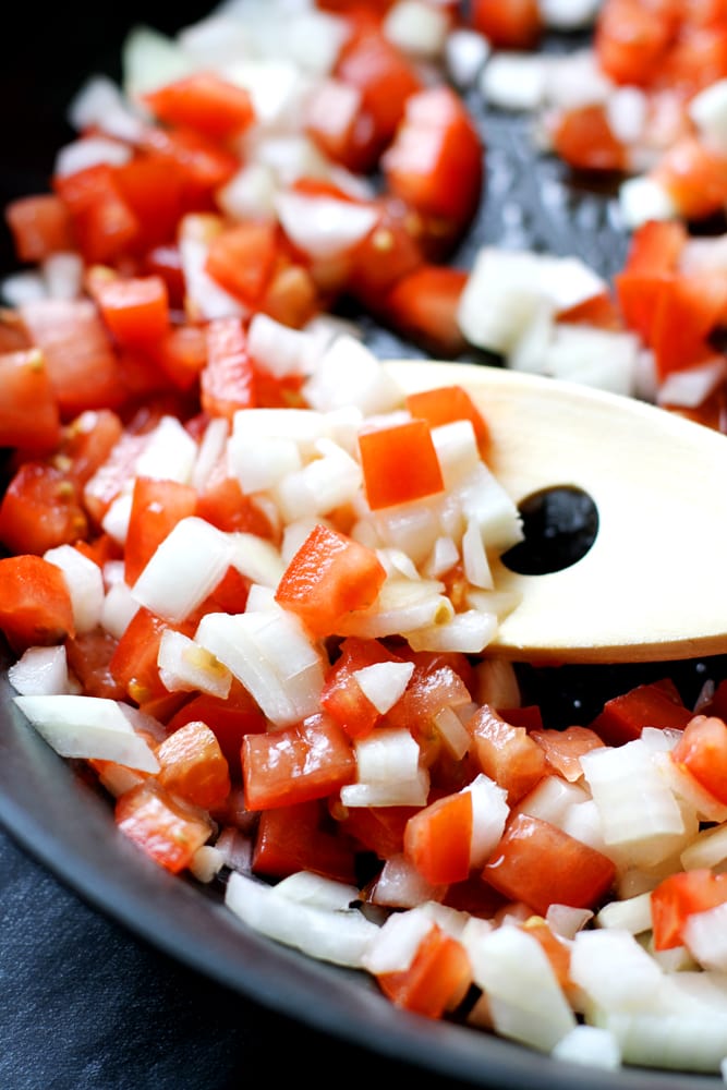 onions and tomatoes cooking in pan