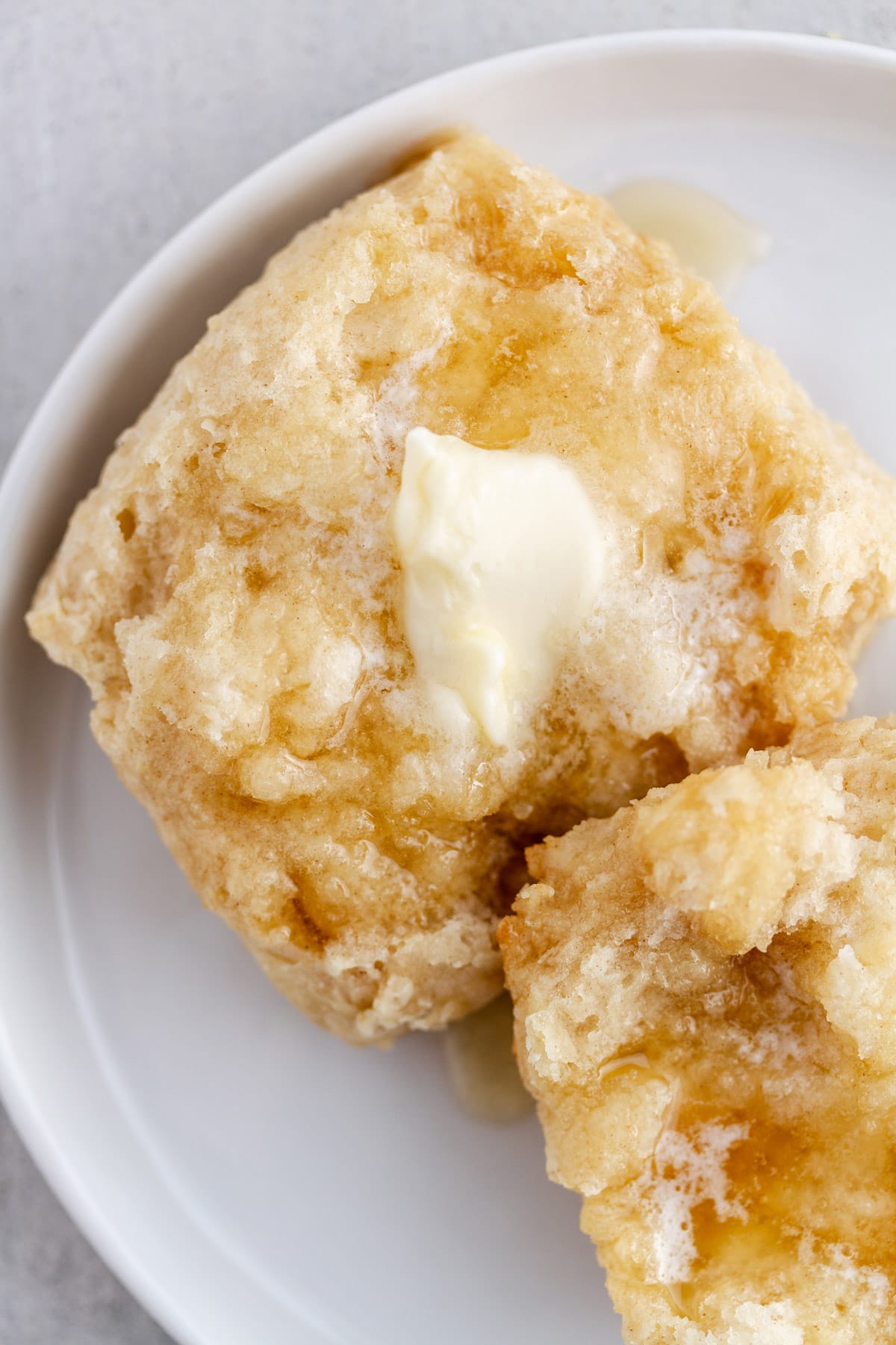 a split southern buttermilk biscuit on a plate with butter and honey on top