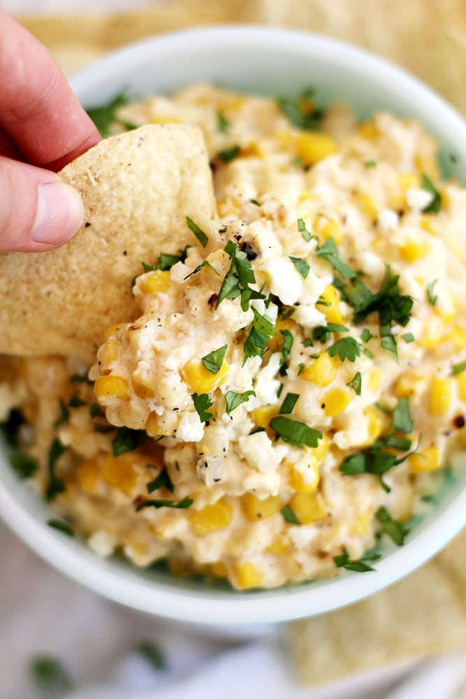 chip dipping into slow cooker Mexican grilled corn dip