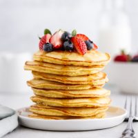 stack of coconut flour pancakes on a plate with berries on top