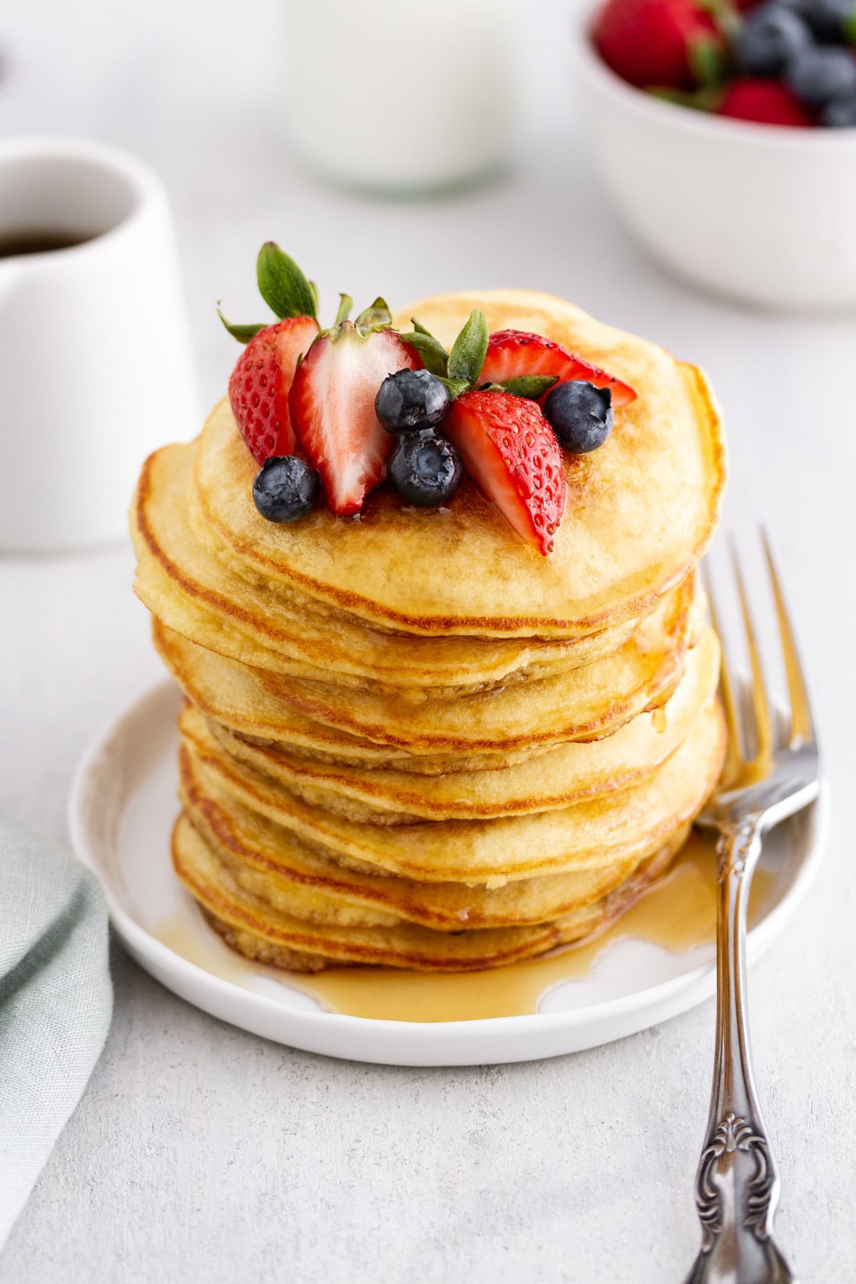 stack of coconut flour pancakes on a plate with berries on top