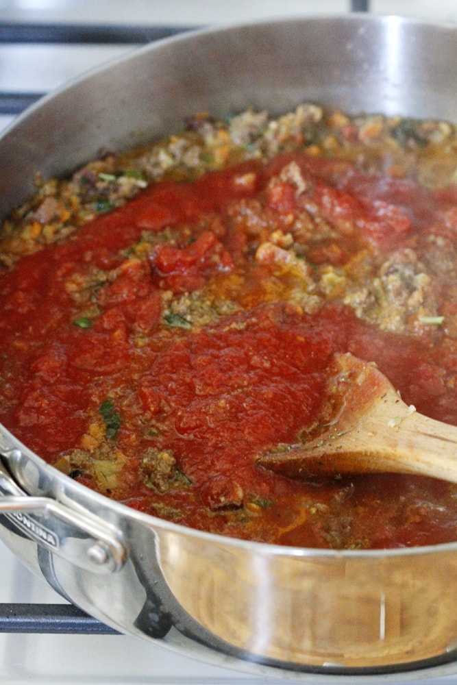 mixing sauce and beef on stove in pot