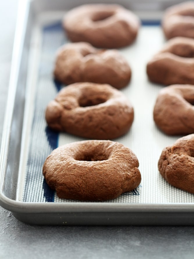 shaped pumpernickel bagels final proofed on baking sheet.
