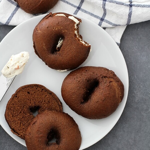pumpernickel bagels on white plate with cream cheese.