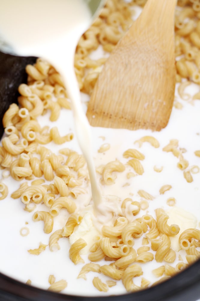 mixing ingredients in slow cooker to make macaroni and cheese