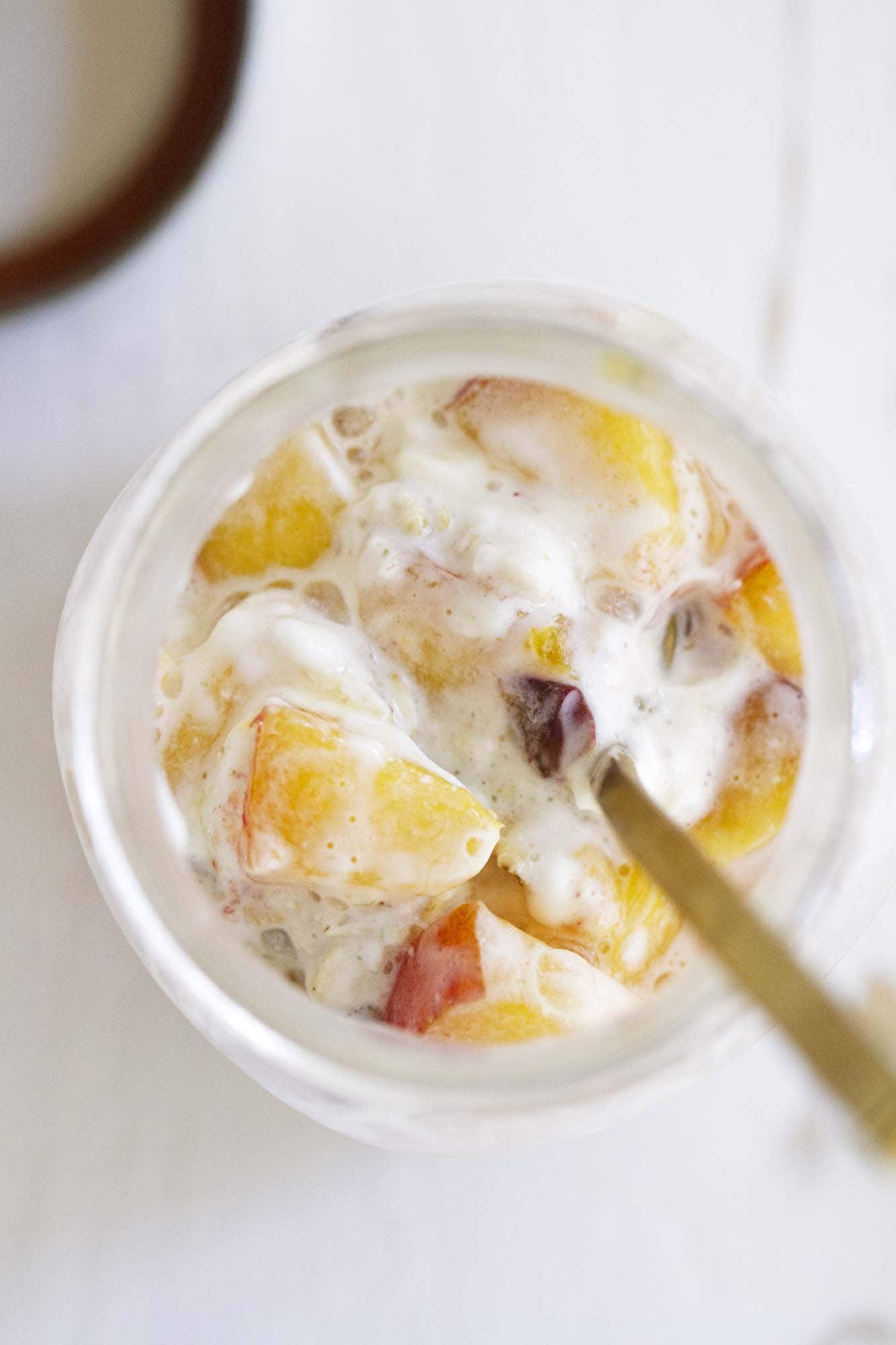 overhead view of peaches and cream overnight oats in a glass jar