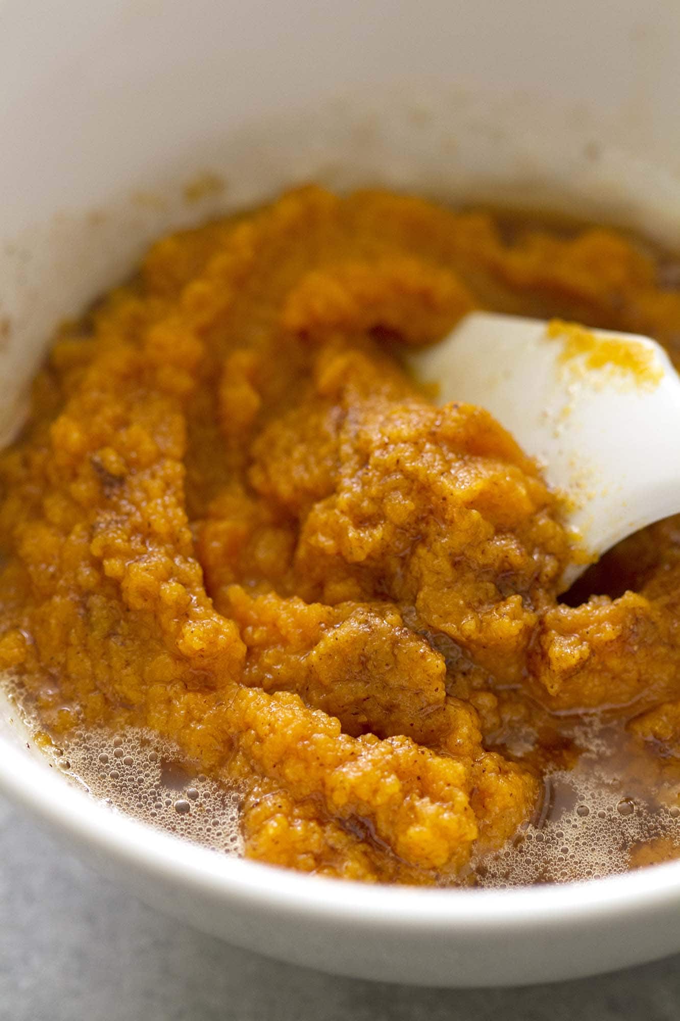 mixing ingredients to make pumpkin cinnamon rolls in bowl