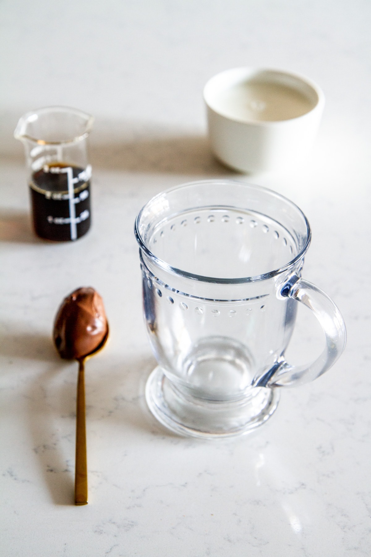 spoonful of hazelnut spread next to glass mug