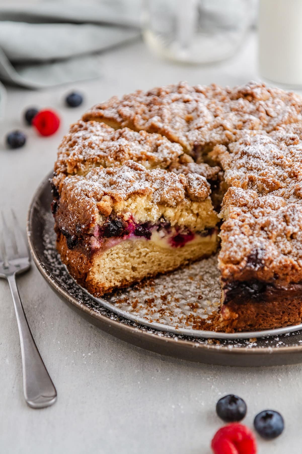 a slice of berry cream cheese coffee cake on a plate with a fork next to it