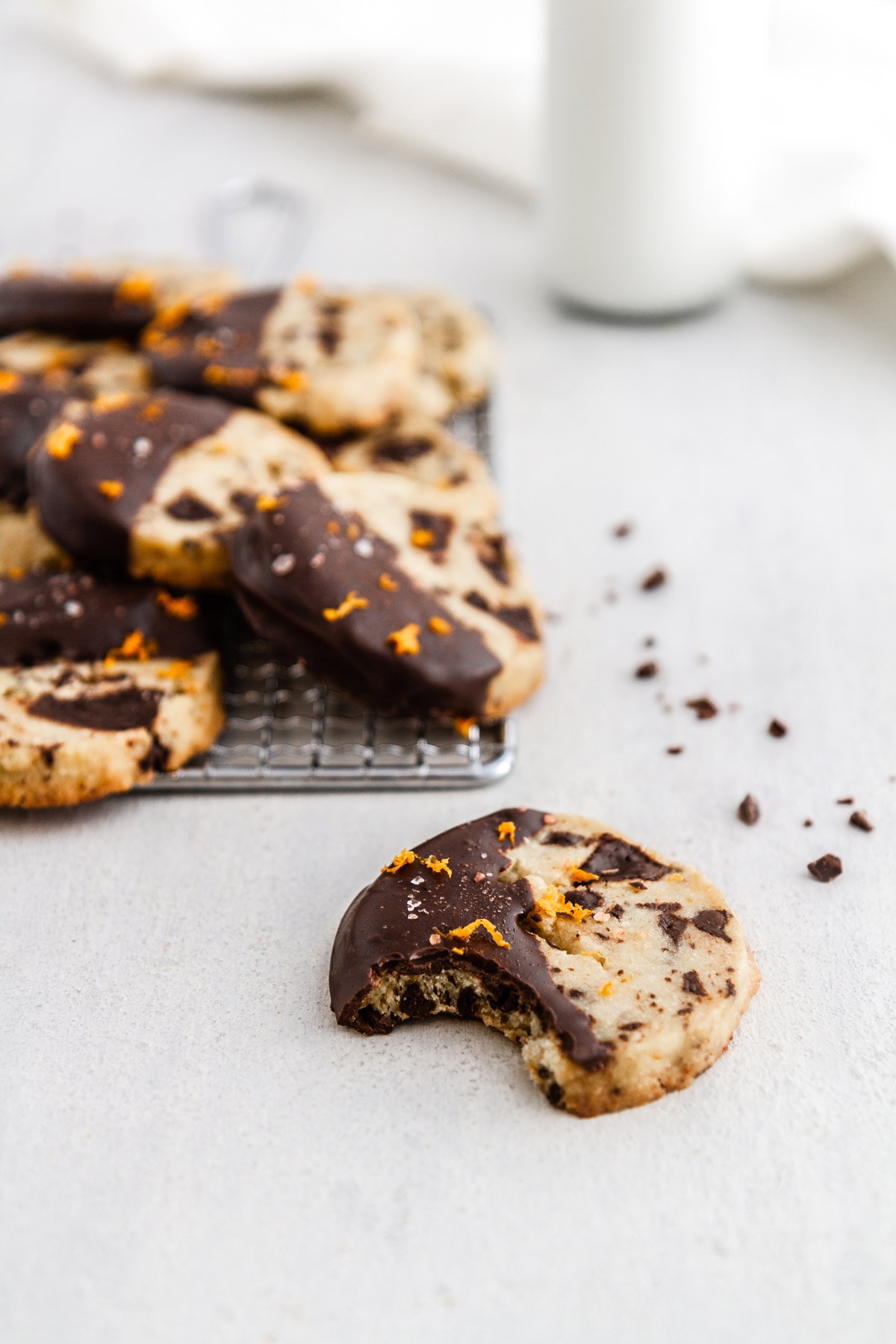 a chocolate orange shortbread cookie with a bite out of it and more cookies in the background