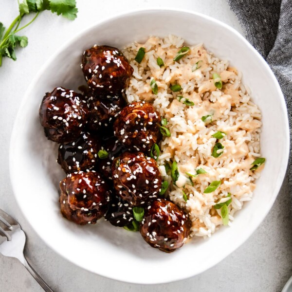 korean bbq meatballs in a bowl with rice with fork off to the side.
