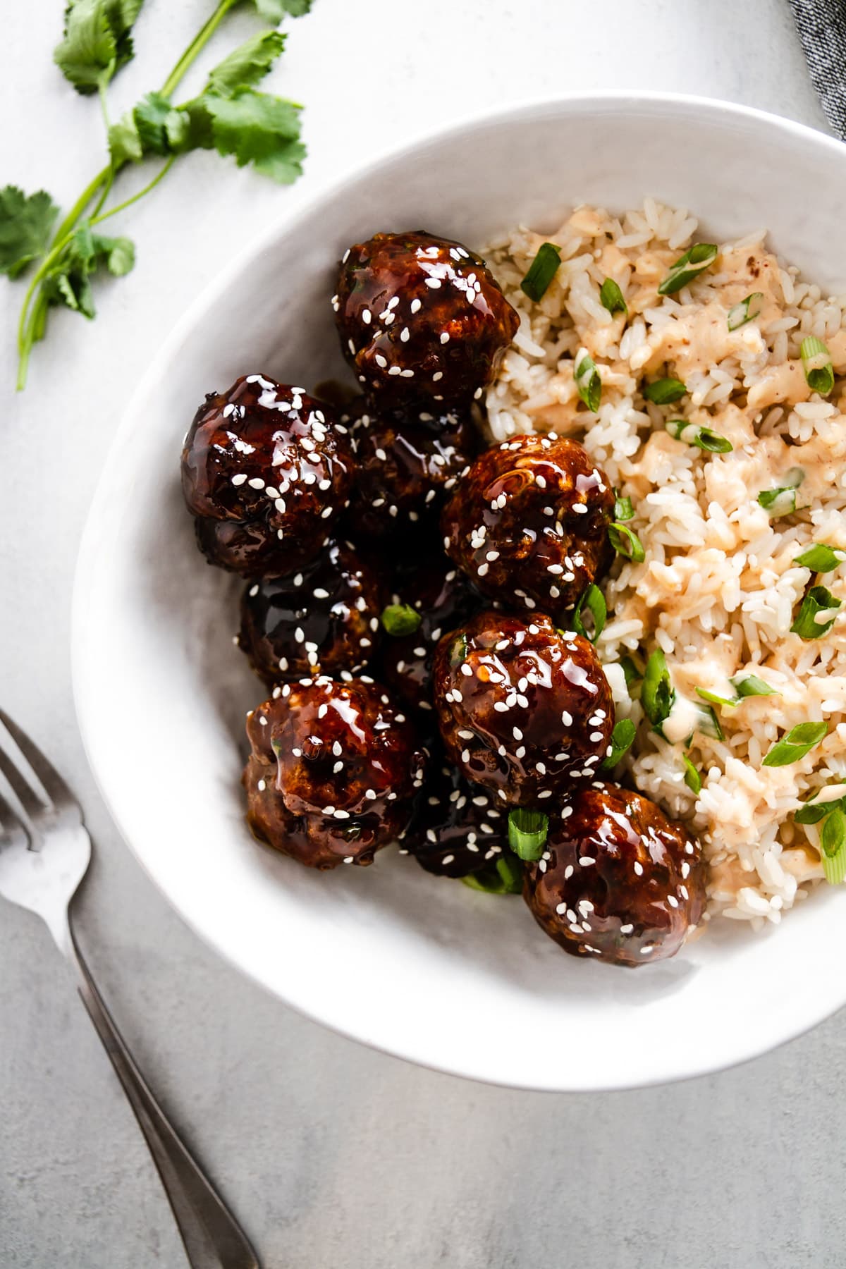 korean bbq meatballs in a bowl with rice and a fork off to the side
