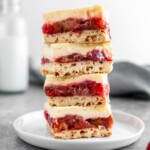 a stack of strawberry rhubarb cheesecake bars on a plate.