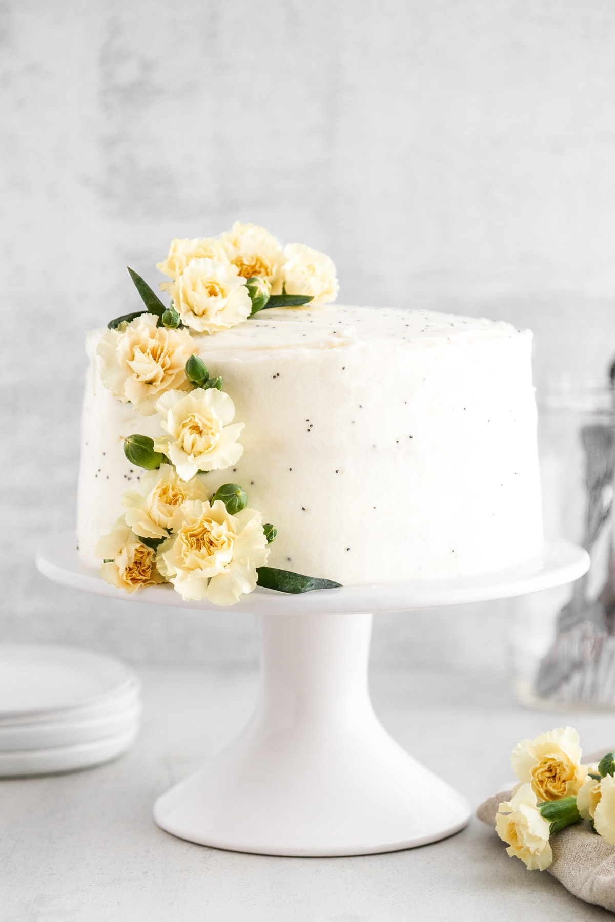 a lemon poppy seed cake on a cake stand