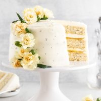 A lemon poppy seed cake on a cake stand with a slice taken out