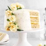lemon poppy seed cake on a cake stand with a slice taken out.