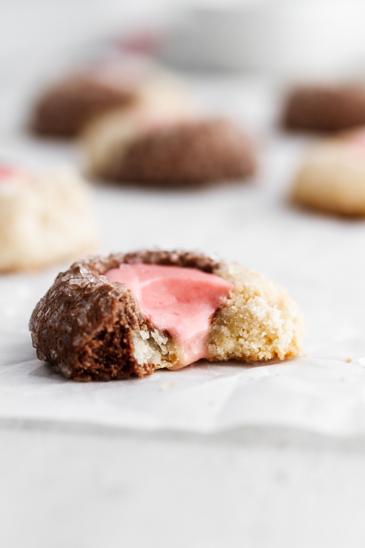 A close-up of a Neapolitan thumbprint cookie with a bite taken out of it