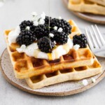 sourdough waffles with berries, whipped cream and syrup pouring.