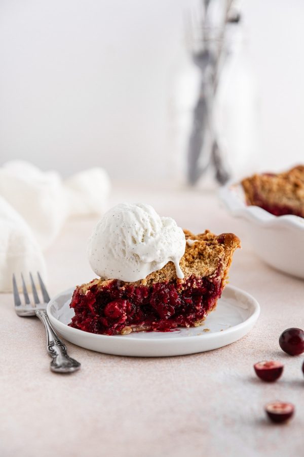 a slice of cranberry crumble pie with ice cream on top