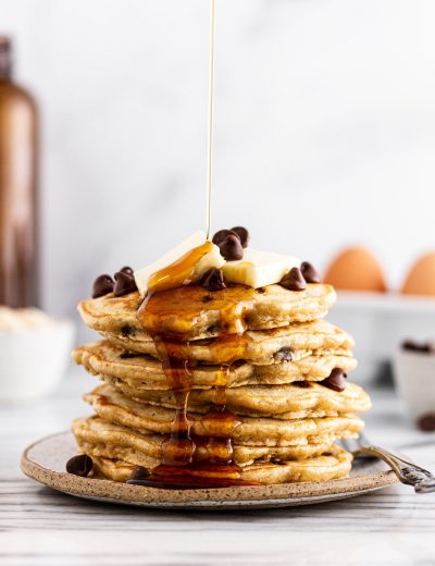syrup pouring onto a stack of oatmeal chocolate chip pancakes