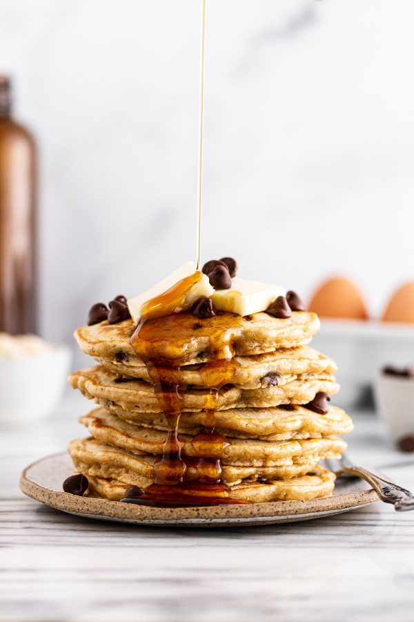 syrup pouring onto a stack of oatmeal chocolate chip pancakes