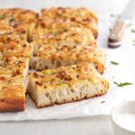 slices of focaccia bread viewed from the side on white parchment.