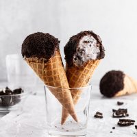 cookies and cream ice cream drumsticks in a glass with a bite taken out of one