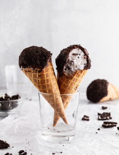 cookies and cream ice cream drumsticks in a glass with a bite taken out of one