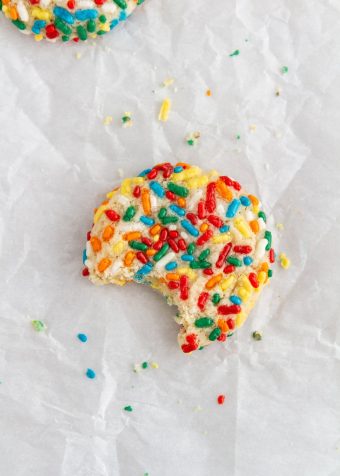 confetti cookie on parchment paper with a bite taken out of it
