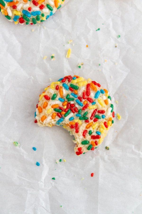 confetti cookie on parchment paper with a bite taken out of it.