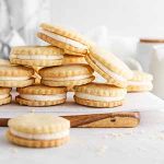 maple cream cookies stacked on a cutting board.